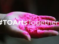 A hand holds pink powder with the text #TOArtsTogether overlaid